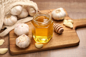 Wall Mural - Jar with honey, garlic and dipper on wooden table, closeup