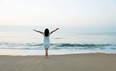 Wall Mural - Happy woman standing on the beach with hands up.