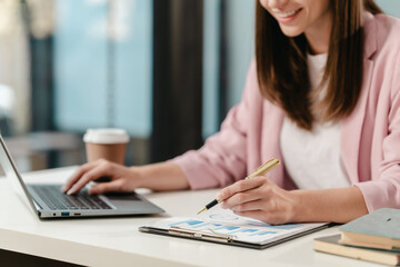 smiling Caucasian university student at a desk with a laptop, likely studying a subject in the humanities.