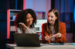 © makibestphoto - African American business worker with an afro presenting a UX,UI design on a clipboard to a Caucasian colleague in an office setting.