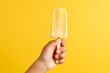 Side view of a child's hand holding fruit ice cream isolated on a yellow background