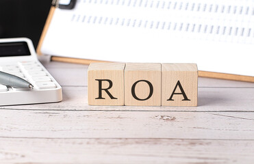 Poster - ROA word on a wooden block with clipboard and calcuator
