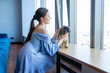 Female rests near windowsill with picturesque view in background. Woman sits with shih tzu in company building with smiling expression