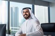 © ckybe - Joyful UAE national in traditional attire working in office, perfect for Middle Eastern business idea.