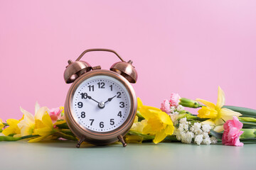 Alarm clock with spring flowers. Spring time, daylight savings concept, spring forward