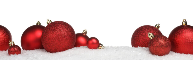 Beautiful red Christmas balls on snow against white background