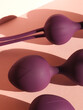 Kegel balls close-up in a soft pink background with shadows and sinuous shapes. Vaginal balls for pelvic floor exersices. Ben wa balls.