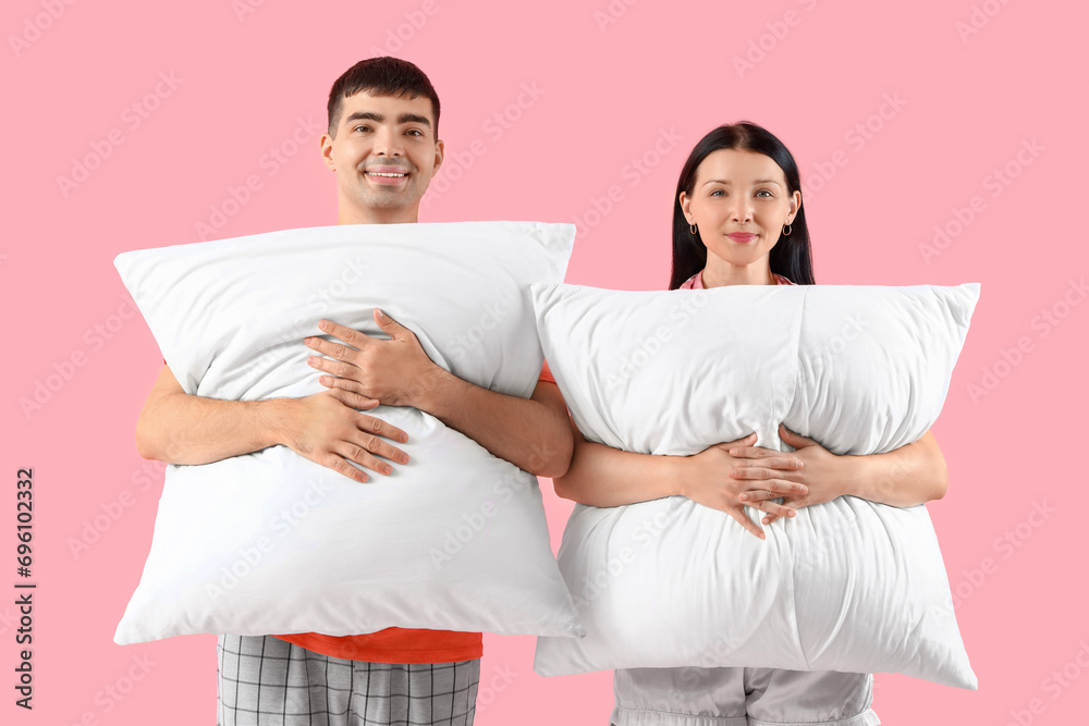 Young couple with pillows on pink background