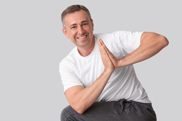 Poster - Mature man doing yoga on light background