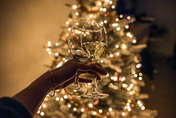 Hand holding two glassed of wine. One is empty and one is filled with wine. Single for Christmas celebration. Grainy and noisy image. Celebrating alone and having fun.