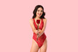 Young happy Asian woman in sexy underwear with beautiful red rose on pink background