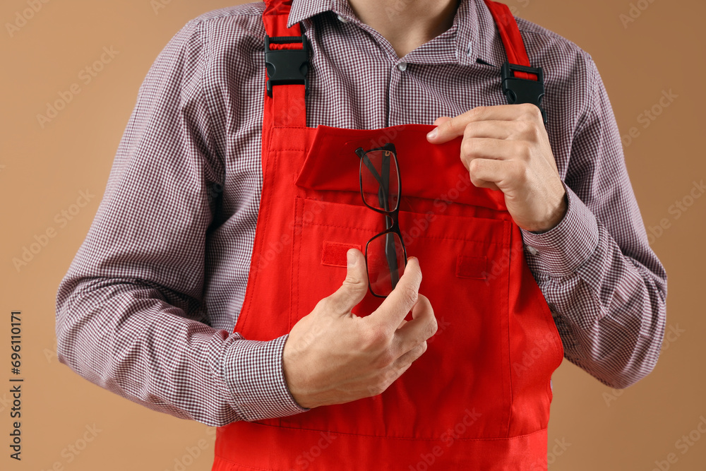 Young male worker with eyeglasses on beige background