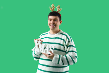 Sticker - Young man in deer horns with Christmas decor on green background