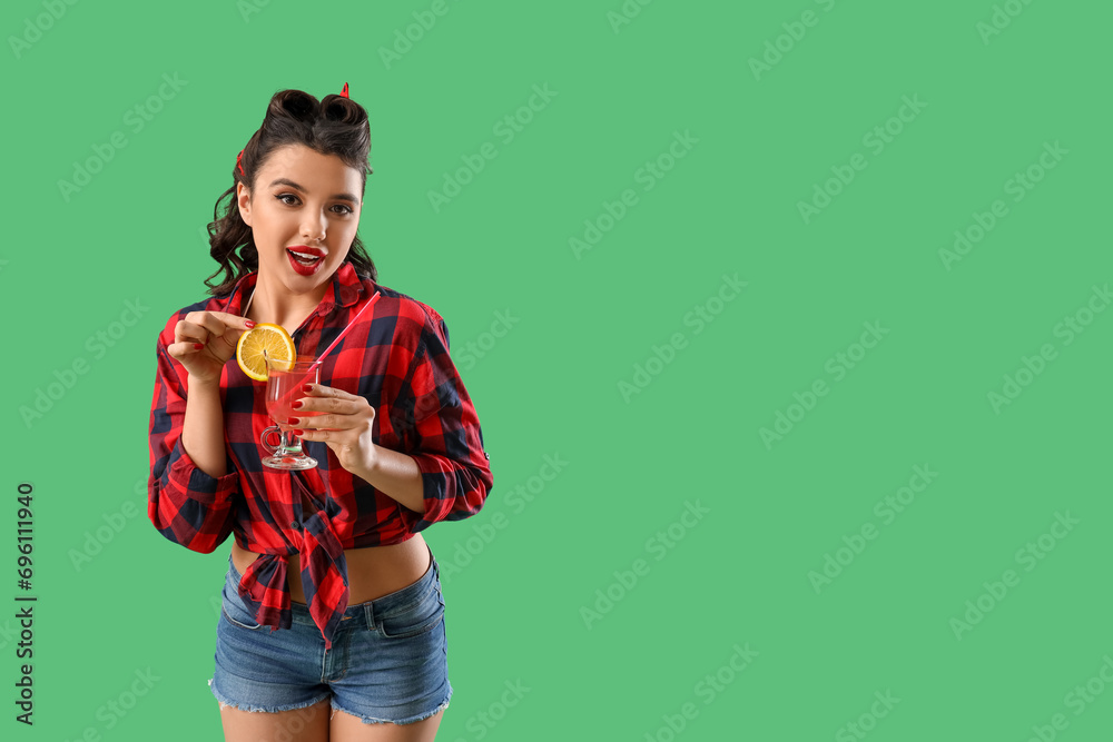 Young pin-up woman with cocktail on green background