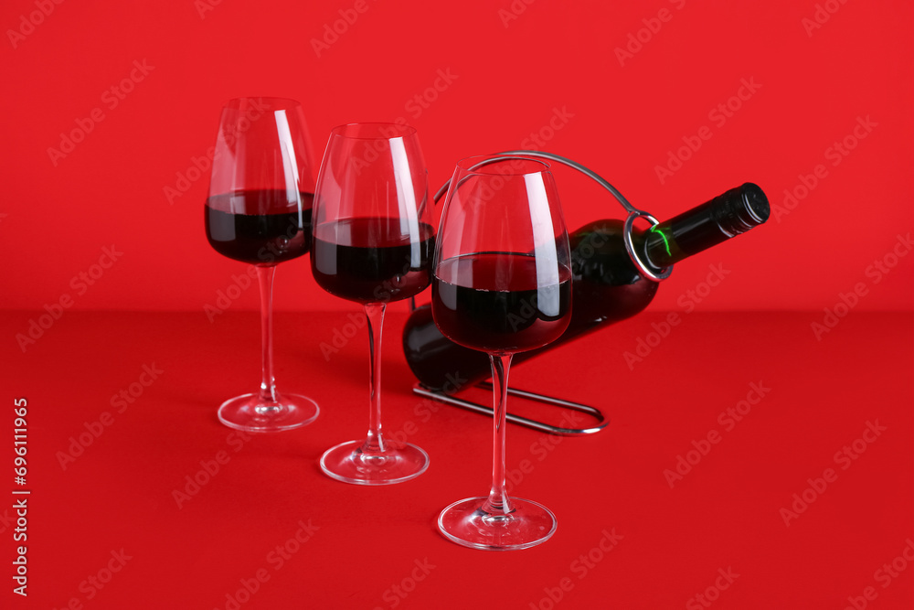 Bottle and glasses of red wine on color background