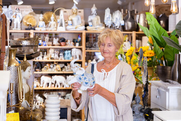 Wall Mural - Elderly positive retired woman chooses an Indian figurine at a hardware store