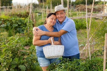 Male and female gardeners with gardening tools posing in garden