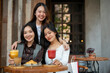 © bongkarn - Three attractive young Asian women are sitting at a table in a restaurant together, hanging out