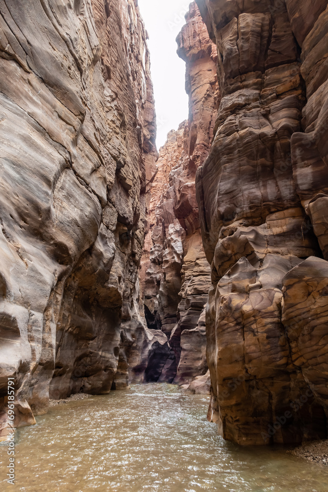 The shallow Mujib River flows in a canyon between high mountains along ...