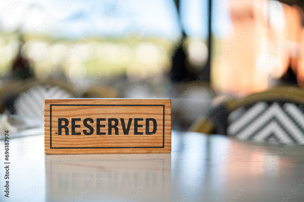 A wooden reserved sign that placed on the dining table at the luxury restaurant for booking the seat. Sign and symbol object photo.