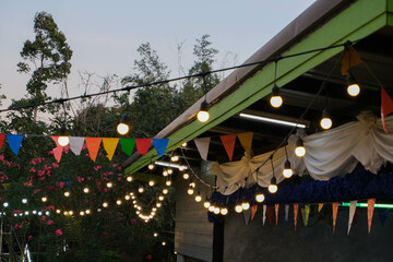 Light bulbs hang on electric wire and party background.