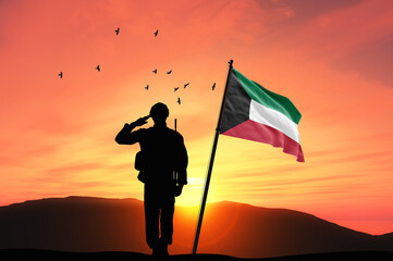 Wall Mural - Silhouette of a soldier with the Kuwait flag stands against the background of a sunset or sunrise. Concept of national holidays. Commemoration Day.