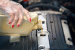 Woman check oil level and top up engine oil. Female hand in protective gloves pouring motor oil. Woman top up engine oil. Pouring motor lubricant from plastic bottle. Selective focus