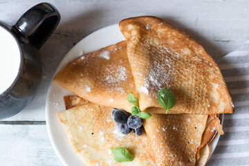 Breakfast: fresh pancakes with berries. On a wooden background. Morning