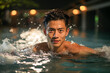 Retrato de un hombre asiático practicando natación en una piscina cubierta.