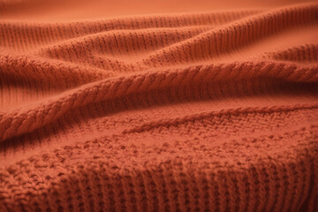 The texture of a knitted sweater in the colors of the year. A full-frame peach sweater. Knitted background for text