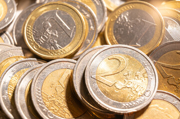 Rows of coins on a white surface, photographed against light and shadow.