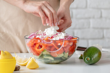 Wall Mural - Woman adding feta cheese to bowl of Greek salad