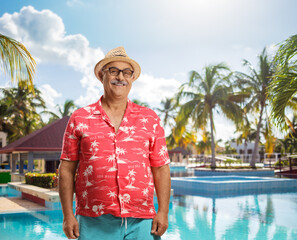 Wall Mural - Male tourist smiling at camera in front of an outdoor swimming pool
