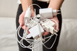 © pridannikov - A woman holds multiple chargers in her hand for devices and chooses compatibility