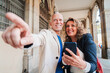 A middle aged mature couple pointing and watching the location on a gps app using a cellphone on a romantic journey trip. Married people sightseeing together and watching places on the smart phone