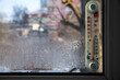 Thermometer behind a window wet with condensation. Selective focus.