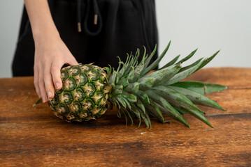 Poster - Organic pineapple held firmly, ready for healthy recipes, on wood.
