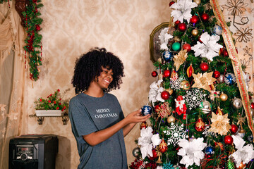 Wall Mural - Beutiful latin girl placing christmas balls on the tree