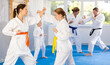 Focused teen girl and woman in kimono practices combat technique of punching and blocking at family martial arts class
