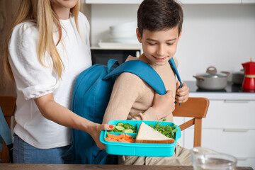 Canvas Print - Mother packing school lunch for her little son in kitchen