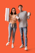 © Pixel-Shot - Young couple with wallpapers and paint cans on orange background