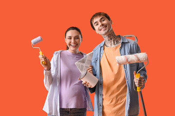 Poster - Young pregnant couple with paint can and rollers on orange background