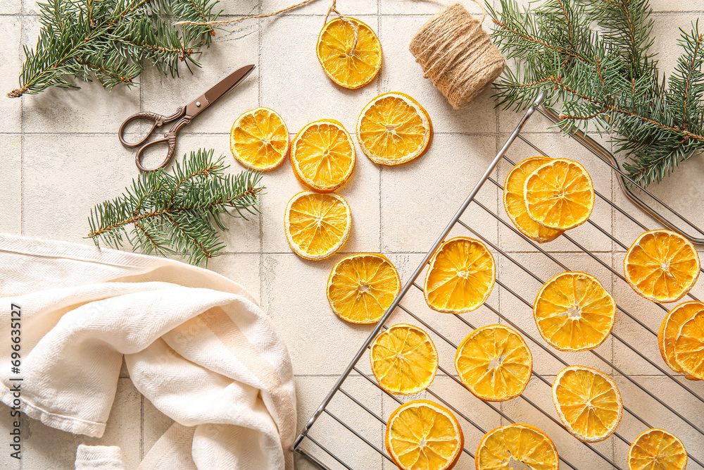 Stand with dried orange slices and fir branches on white tile background