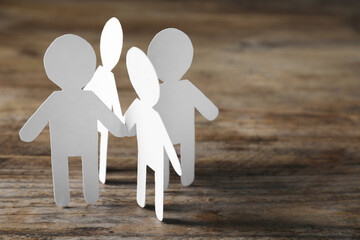 Wall Mural - Teamwork concept. Paper figures of people holding hands on wooden table, closeup and space for text