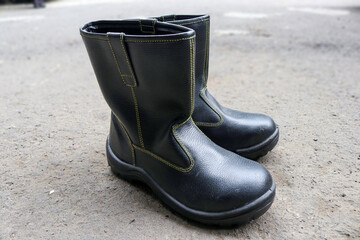 Wall Mural - Photo of black leather boots, on gravel near the building being built