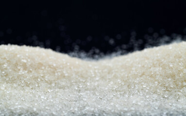 Wall Mural - Pile of white sugar crystals on black background