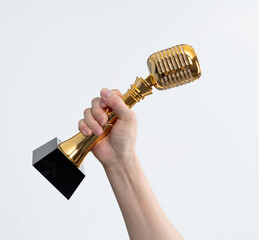 Wall Mural - Hand holding golden microphone trophy on white background