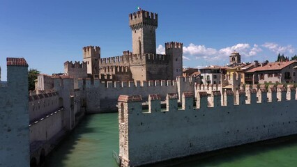 Wall Mural - The historical part of the city of Sirmione on Lake Garda in Italy, slow motion shot by drone. Scaliger Castle of the city of Sirmione 4K video on drone. Sirmione drone view, climb up