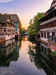 Wall Mural - Ornate traditional half timbered houses with blooming flowers along the canals in the Petite France district of Strasbourg, Alsace, France at sunset