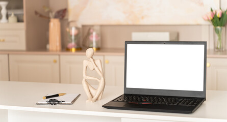 Laptop computer with blank screen mock up and human statuette on psychologist desk. Mental therapy, psychological online consultation, support, hot line, mental clinic concept, app, web site.